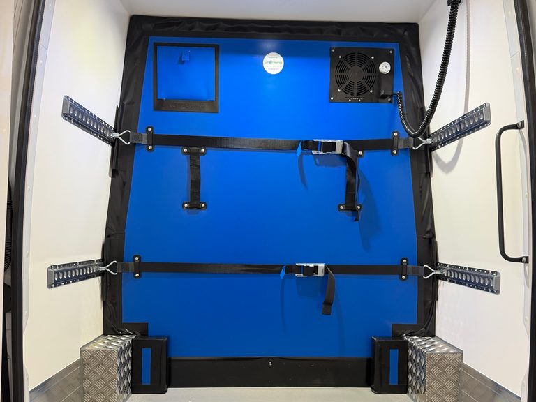 A moveable bulkhead strapped across the load space of a GRV4 fridge van
